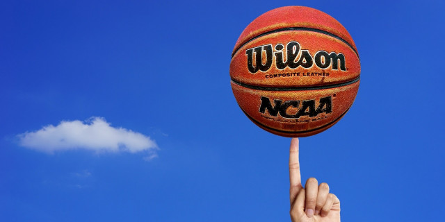 Wilson basketball with NCAA logo, held up against blue sky background.